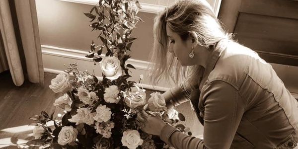Woman arranging a bouquet of roses indoors.