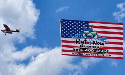 Airplane towing an American flag advertising irrigation service.