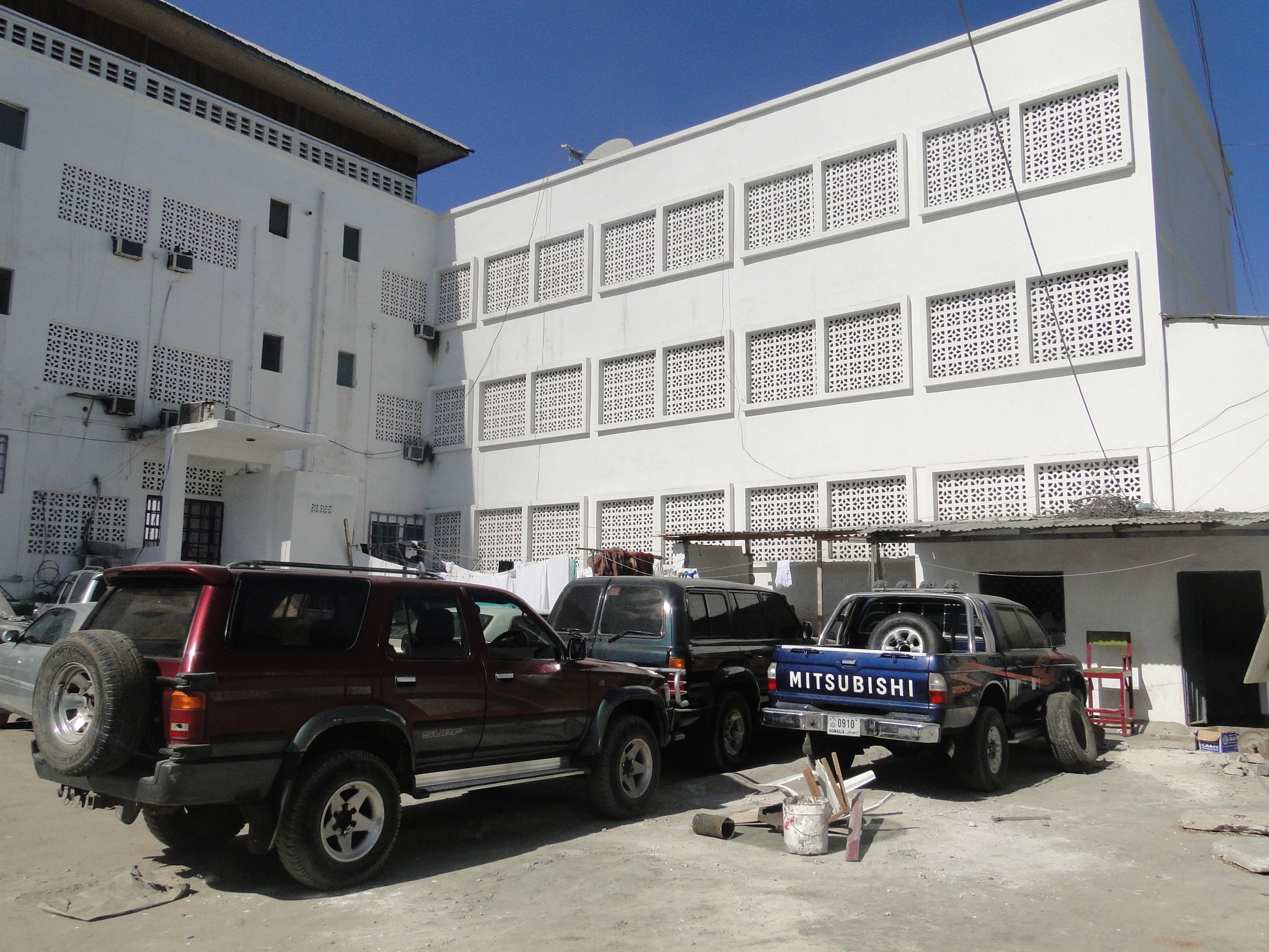 Three parked SUVs next to a white building.