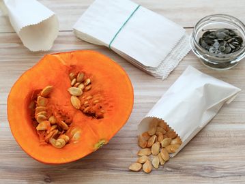 Pumpkin halves with seeds and seed packets on a table.