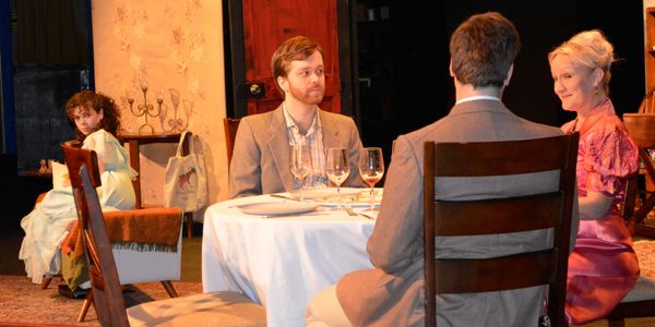 Laura looks over her shoulder toward the family and gentleman caller having dinner.