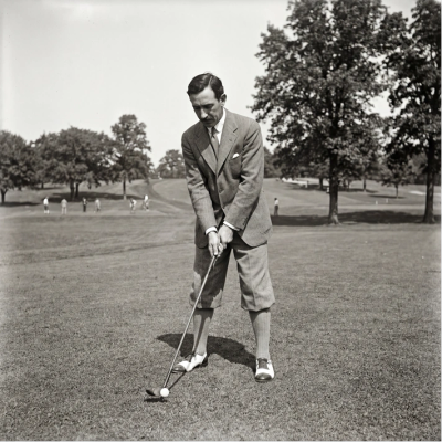 Man in vintage attire preparing to play golf.