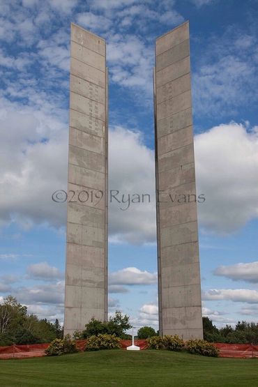 Two tall concrete pillars stand against a partly cloudy sky.