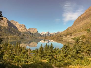 Serene mountain lake reflecting clear blue sky and surrounding peaks.