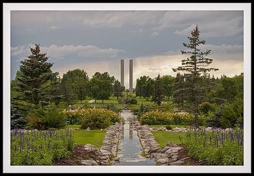 A serene garden with a water channel and two tall pillars in the background.