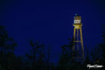 Illuminated water tower at night against a dark sky.