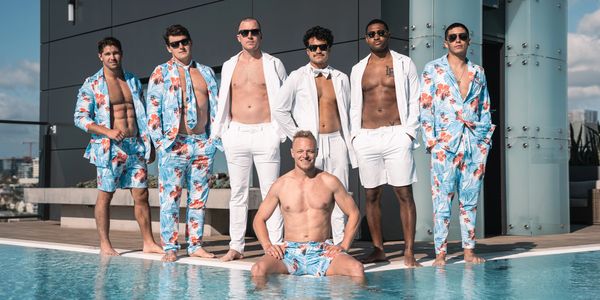 Men standing and sitting poolside wearing suits made from swimsuit material