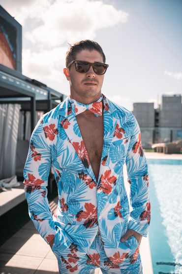 man next to pool wearing hibisicus suit jacket and bow tie