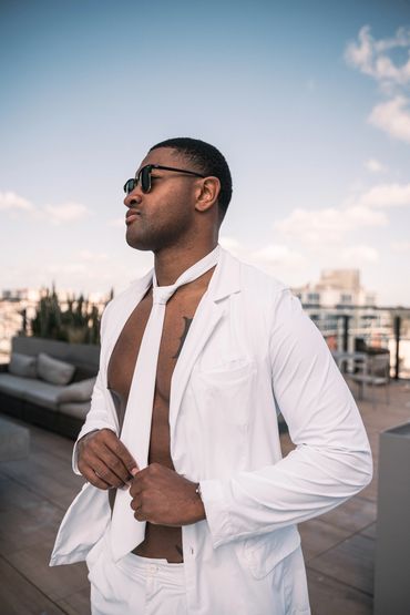 african american man standing at the pool wearing a white swim suit and tie