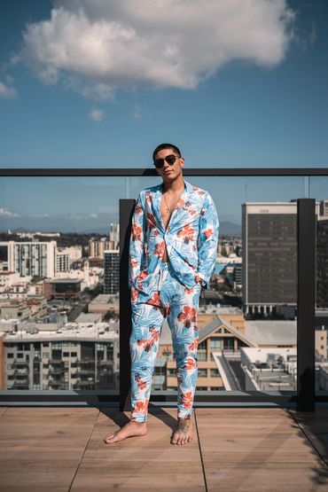 man standing at rooftop pool wearing hawaiian hibisicus swim suit jacket and joggers