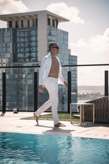 man in all white swim in suit walking next to the pool 