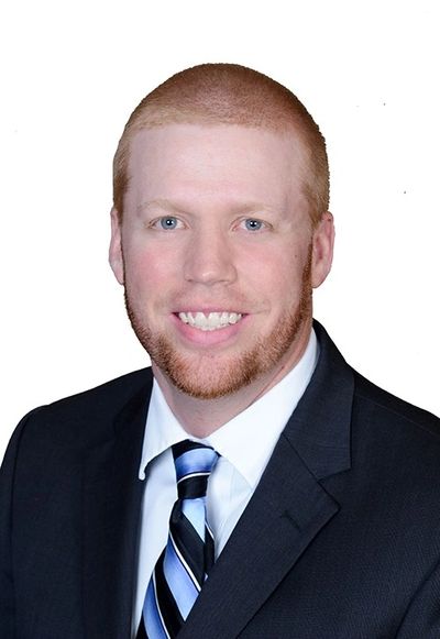 Professional headshot of a smiling man in a suit and tie.