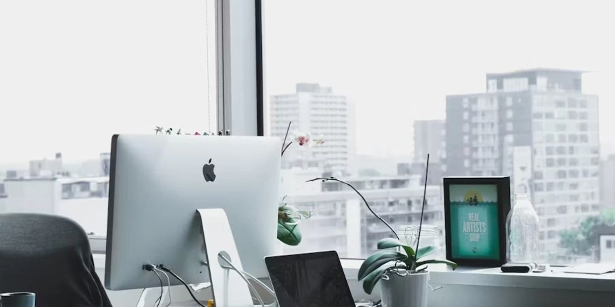 Modern office desk with Apple computer and city view.