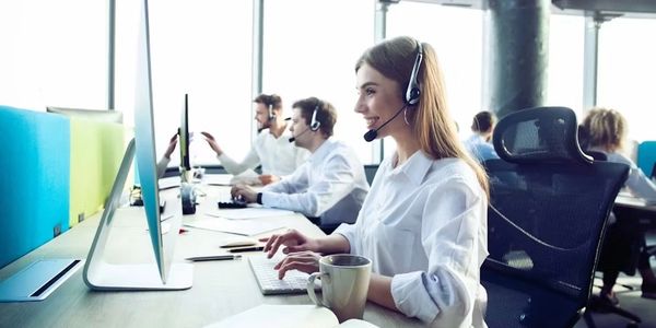 Call center employees working with headsets in a bright office.