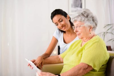 an elderly and young woman watching a tablet 