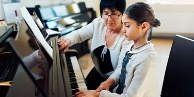 a woman teaching piano to a girl 