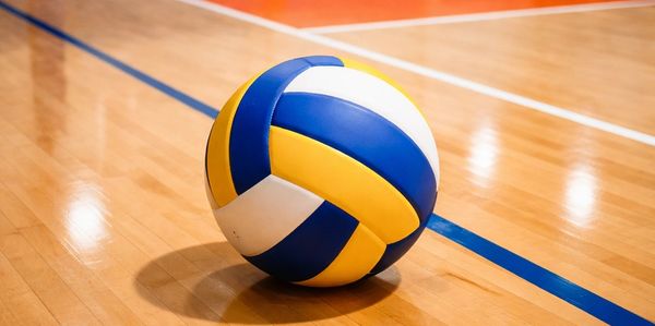 A volleyball resting on a polished indoor court floor.