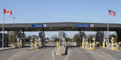 Border crossing checkpoint between Canada and the United States with flag poles.