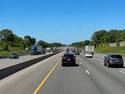 Busy highway with multiple lanes and vehicles under a clear blue sky.