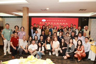 Group photo of people at a formal event with a red backdrop.