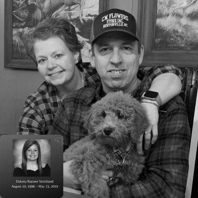 A couple smiling with their dog, embracing warmly indoors.