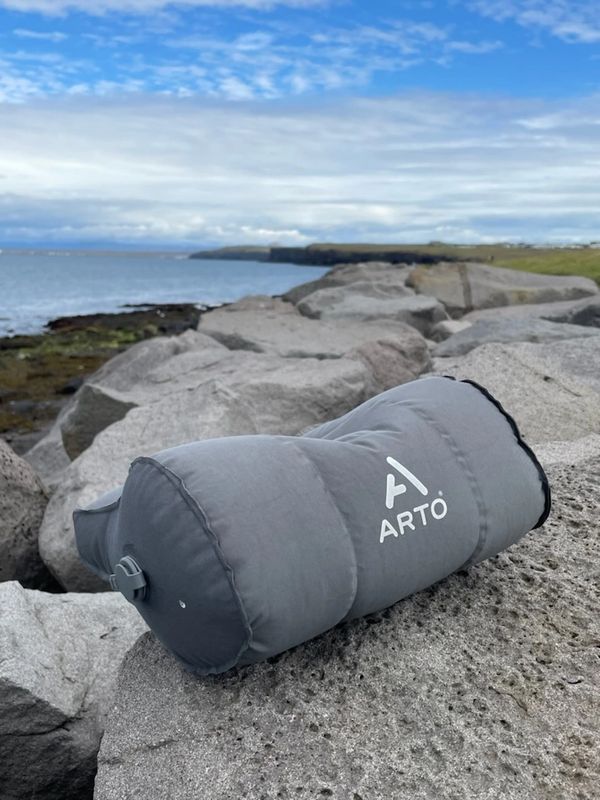 The Arto Pillow - Inflatable sitting on rocks, overlooking a body of water.