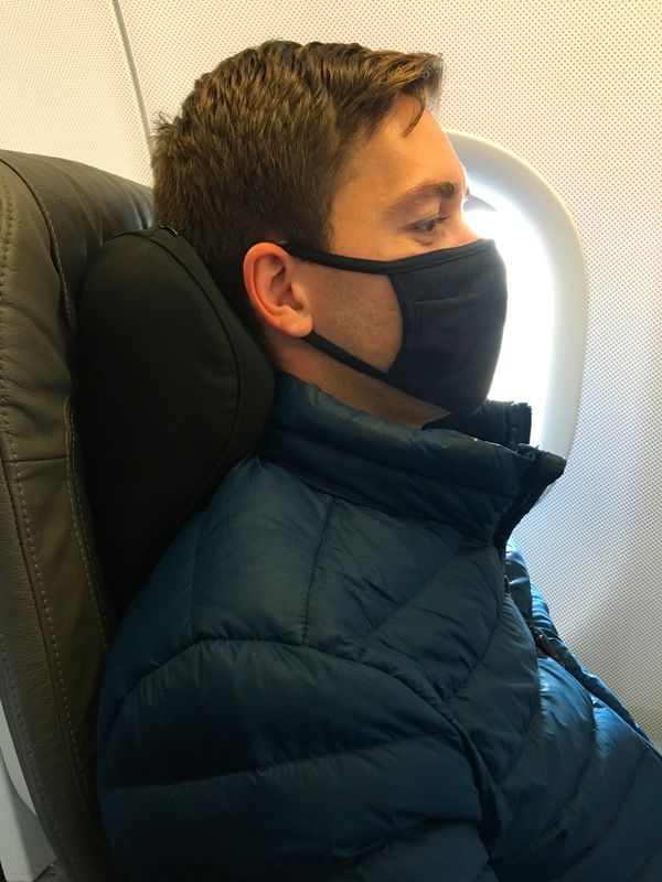 Man using an Arto Pillow - Memory Foam while sitting in an airplane seat.