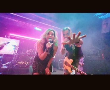 Two performers engaging the audience energetically on stage with vibrant lighting.