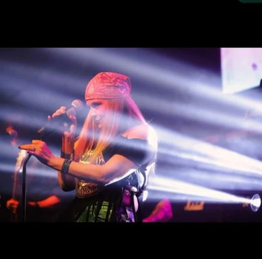 Female singer performing passionately on stage with dramatic lighting.
