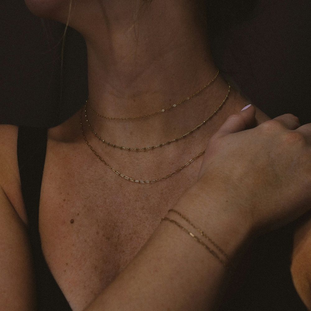 A woman with gold chain necklaces and bracelets