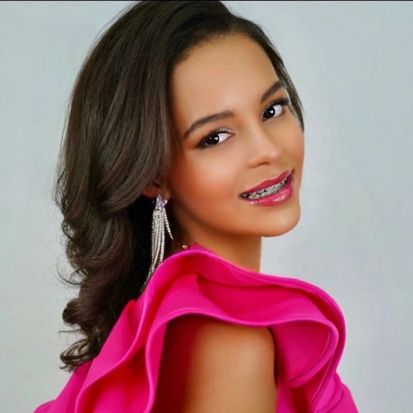 Young woman with braces in a pink dress smiling.