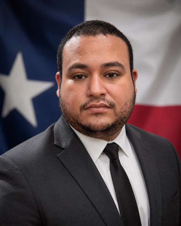 Man in suit with Texas flag background.