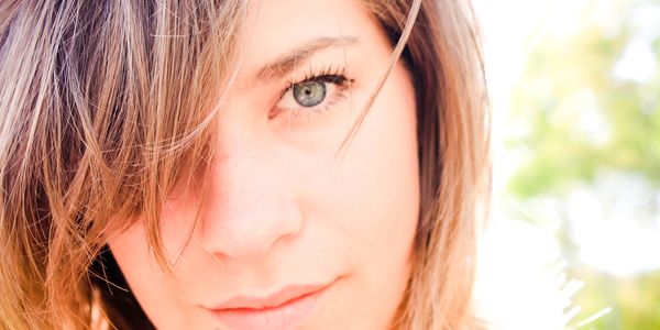 woman looksintot eh camera with light and laughter in her eyes, crisp hair , blurred eyes, bright 