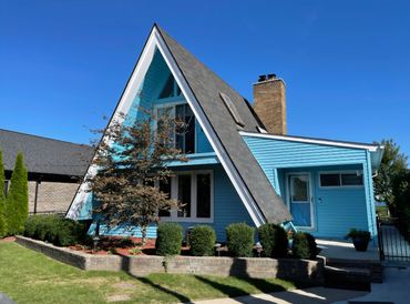 Bright blue A-frame house under a clear sky.