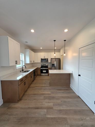 Modern kitchen with wood and white cabinets, stainless steel appliances, and pendant lighting.