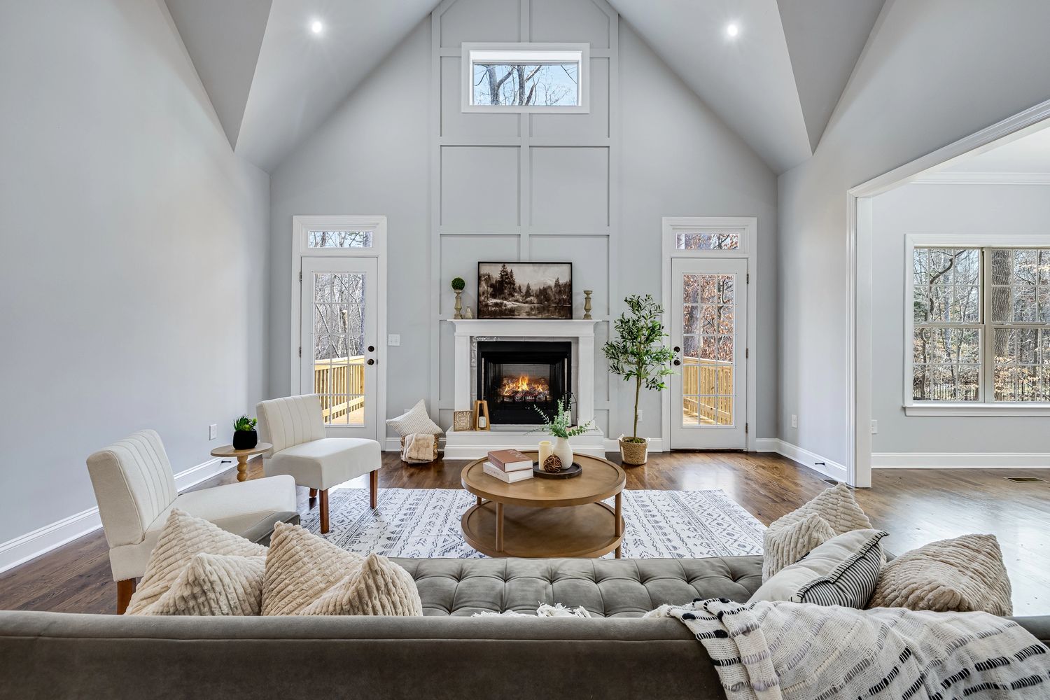 Bright modern living room with fireplace, neutral furniture, and large windows.