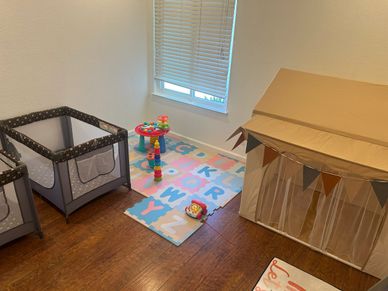 A cozy play area with a playpen, alphabet mat, and a toy tent.