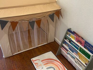 Cozy children's reading nook with a tent, bunting, and a book rack.