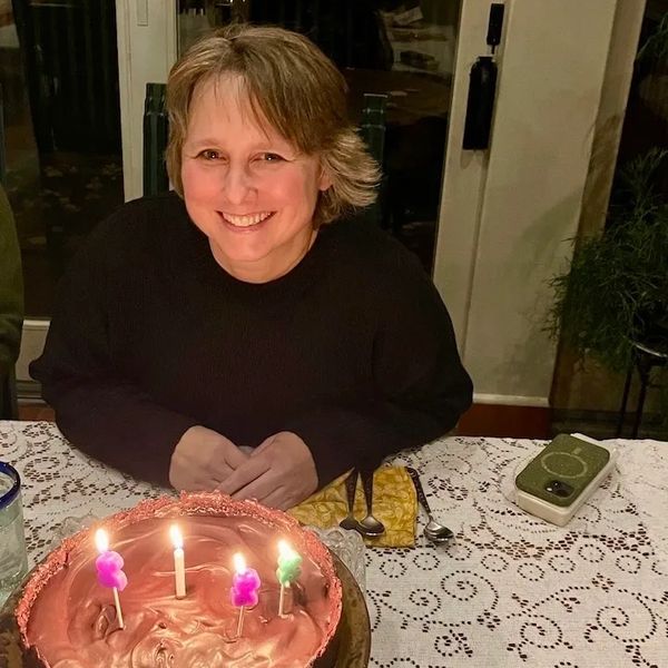 A photograph of a smiling woman with a birthday cake.