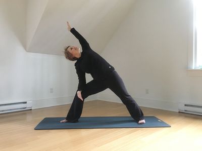 A photograph of a woman doing a standing yoga pose.