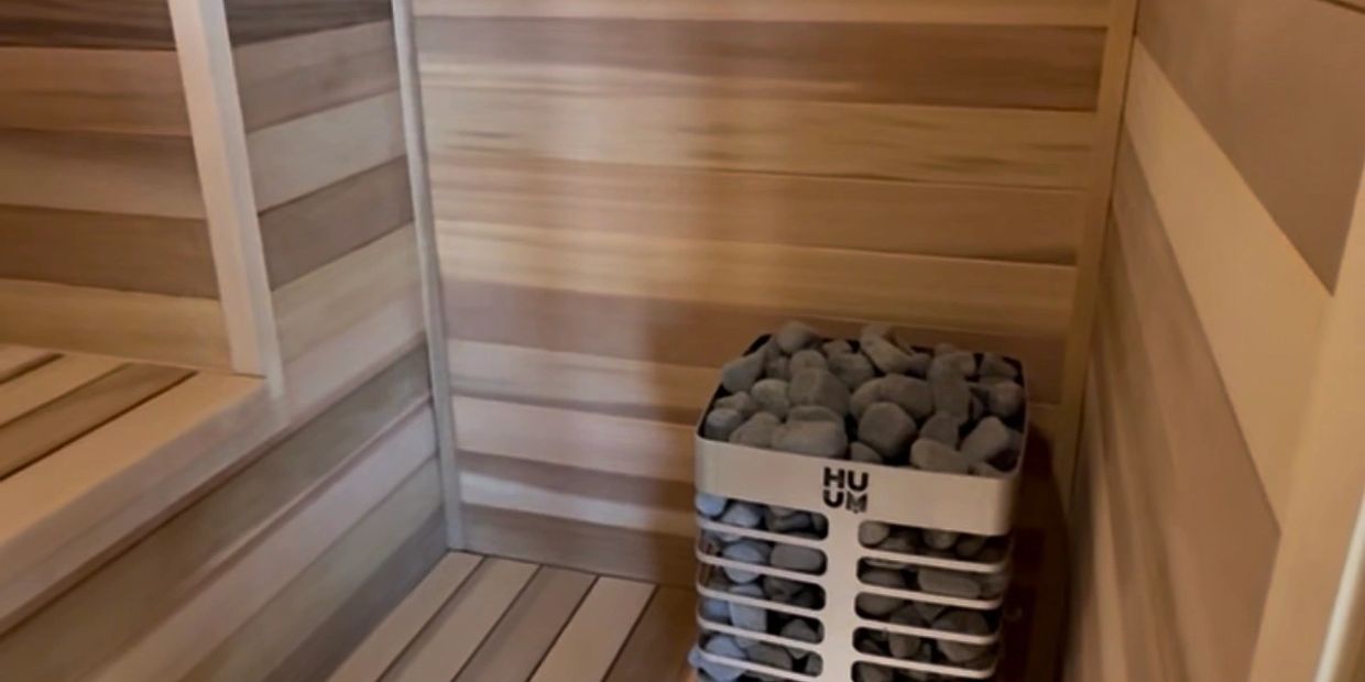 Wood-paneled sauna with a modern stone heater.