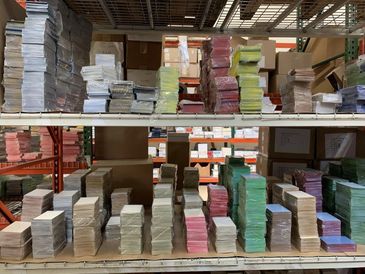 Stacks of colorful paper and envelopes organized on warehouse shelves.