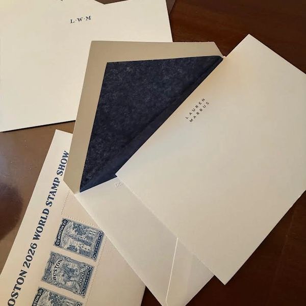Elegant envelopes and vintage stamps arranged on a wooden surface.