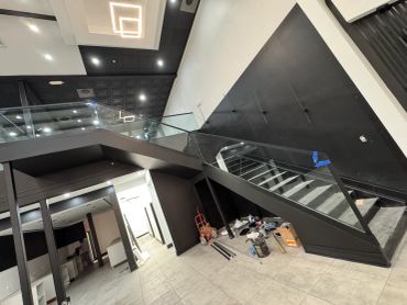 Modern interior under construction with glass railing and geometric ceiling lights.