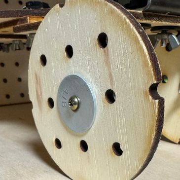 Close-up of a wooden wheel with holes and a metal center.