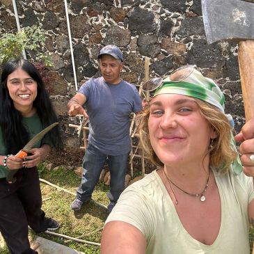 Tres personas trabajando en la jardinería, sonriendo a la cámara.
