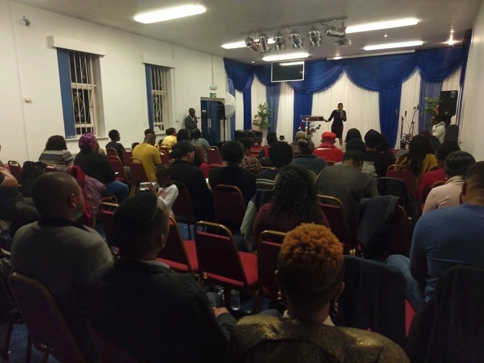 A congregation facing the pulpit in a church hall.