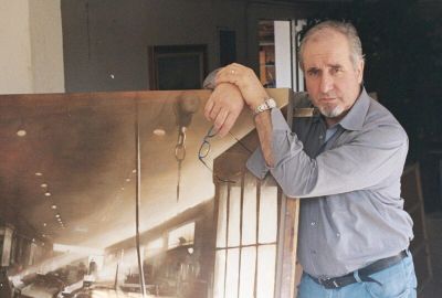 Uomo con camicia grigia che tiene una grande fotografia.