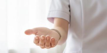 Person in white uniform extending an open hand forward.
