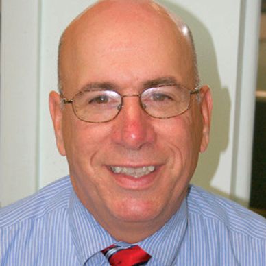 Smiling bald man wearing glasses and a striped shirt.